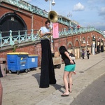 Jen donates some coins to a tuba blowing man with long legs.