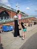 Jen donates some coins to a tuba blowing man with long legs.